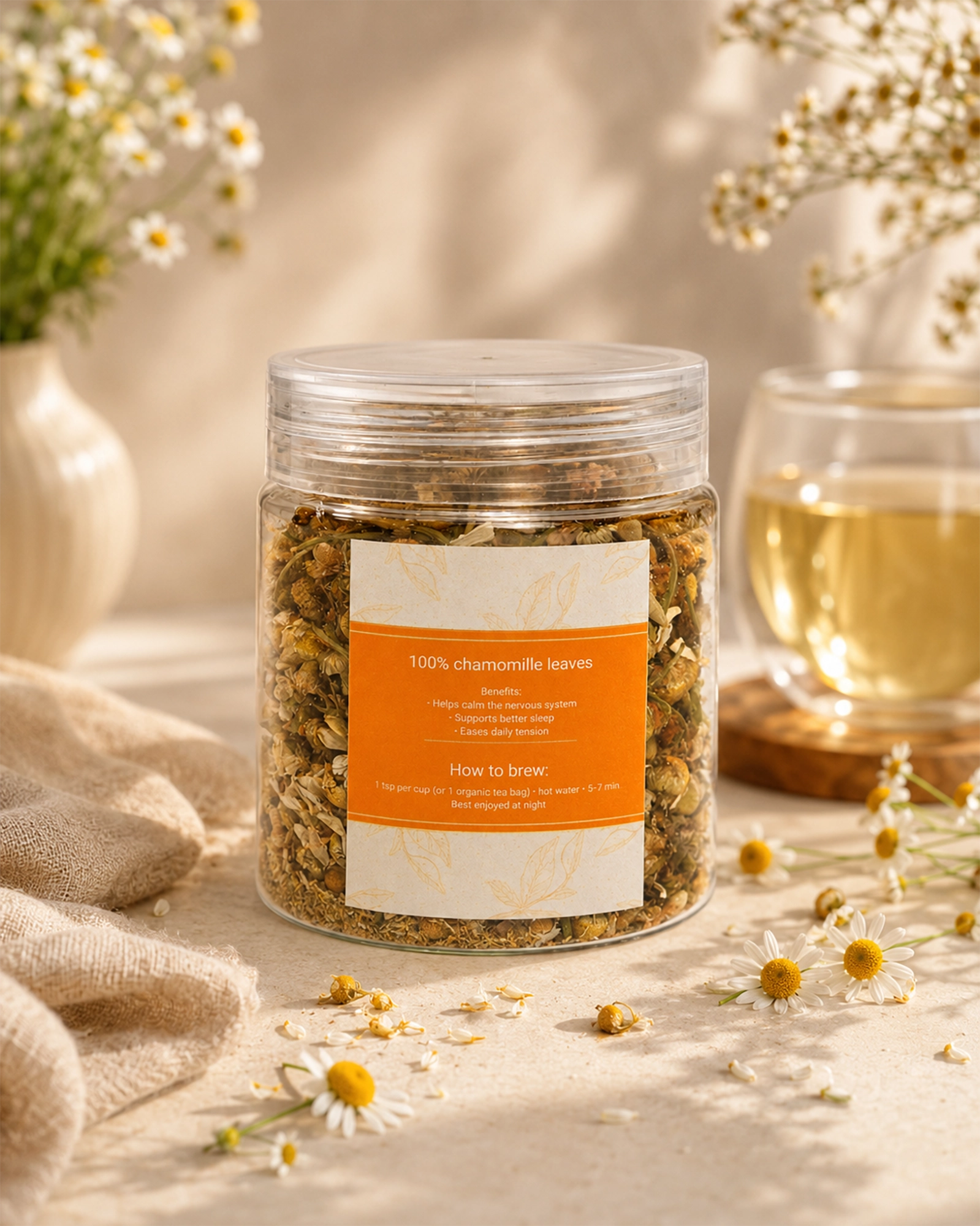 Jar of Calmo-Tea chamomile herbal tea with orange label, chamomile flowers, and a cup of tea on a neutral beige background.