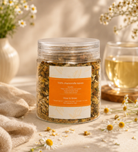 Jar of Calmo-Tea chamomile herbal tea with orange label, chamomile flowers, and a cup of tea on a neutral beige background.