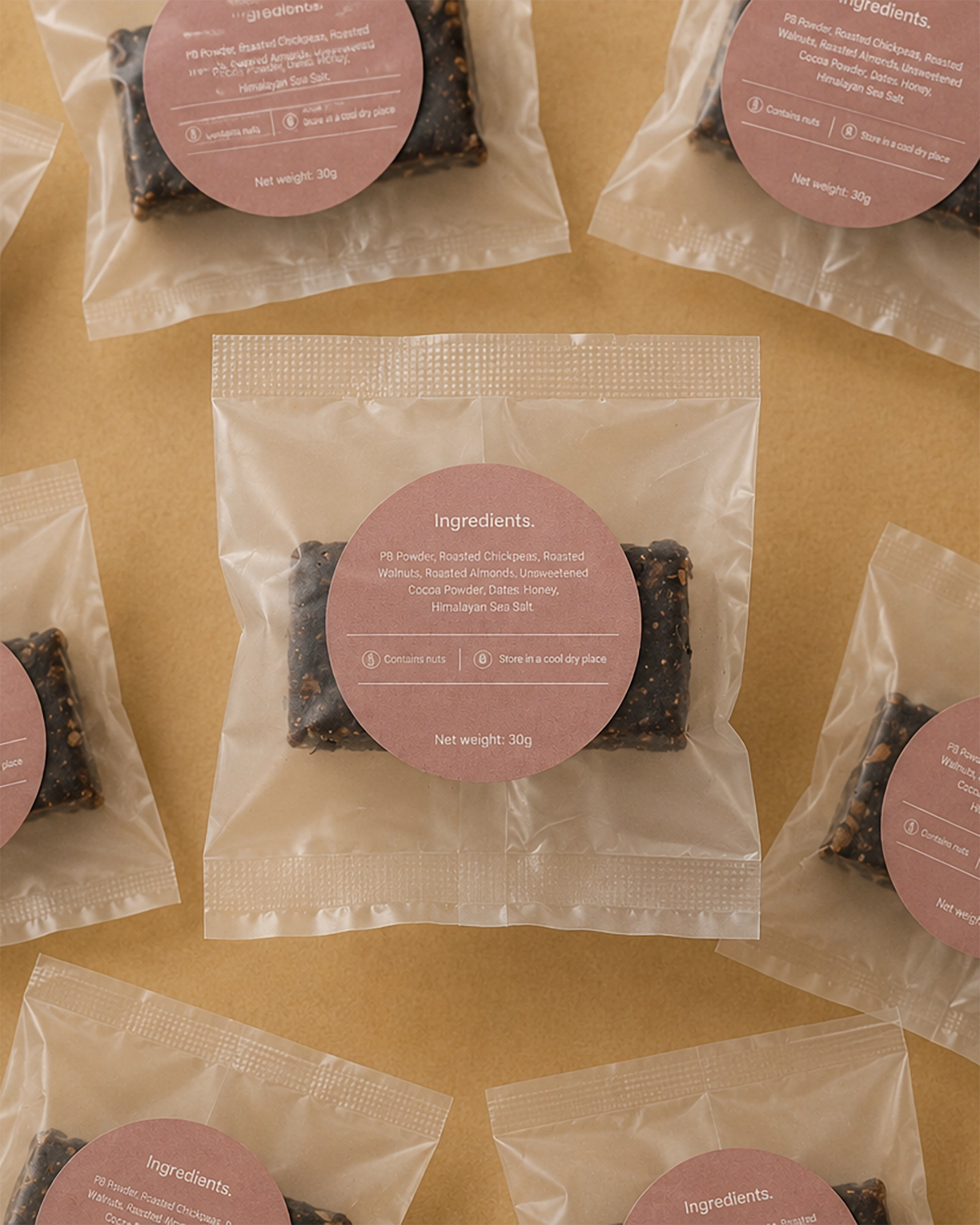Brüt Bar chocolate mini packages with pink labels arranged on a beige background.