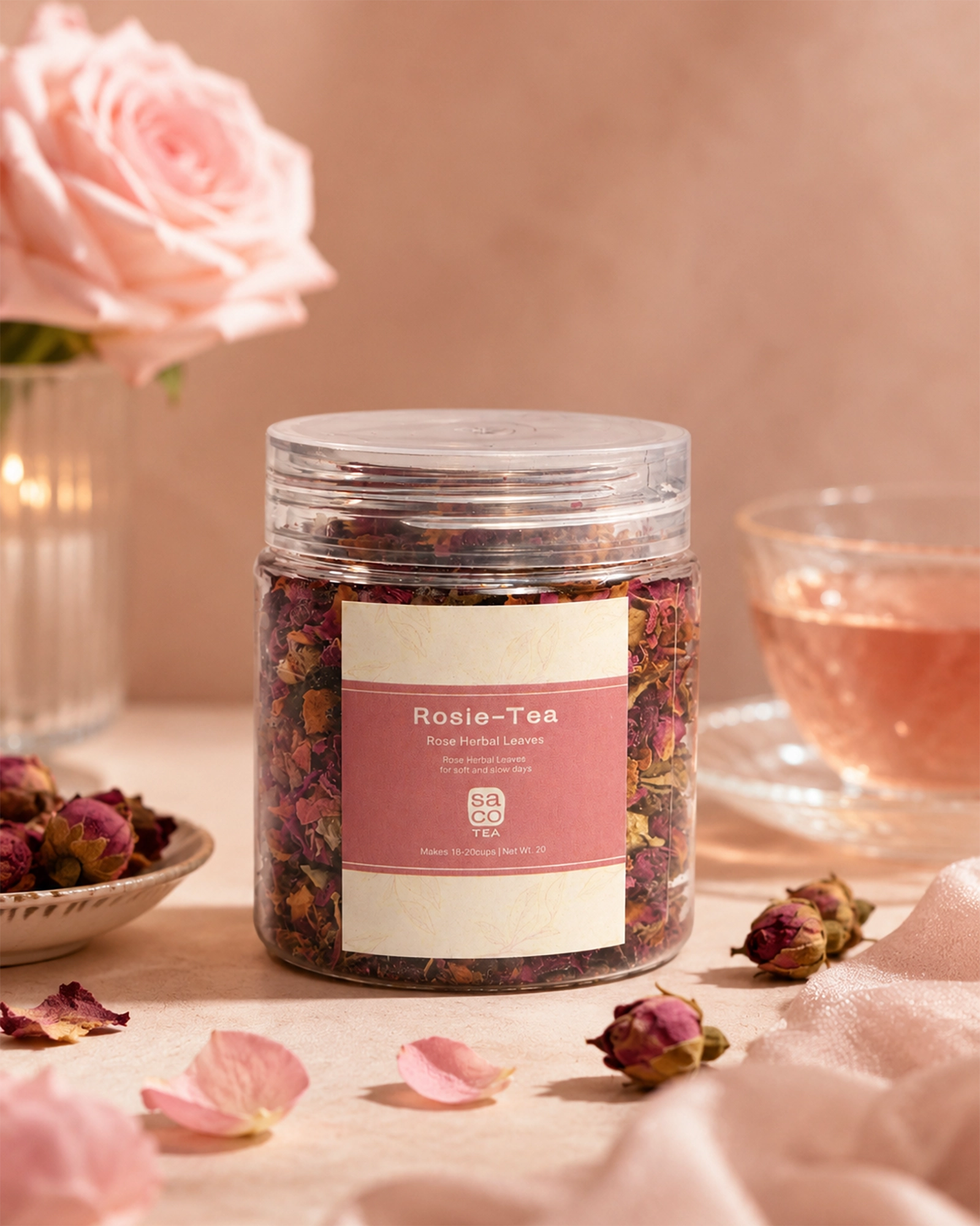 Jar of Rosie Tea with pink label beside rose petals, a cup of tea, and soft floral styling.