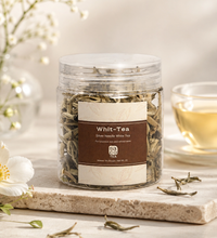 Jar of Whit-Tea with a glass of tea in the background on a light surface.