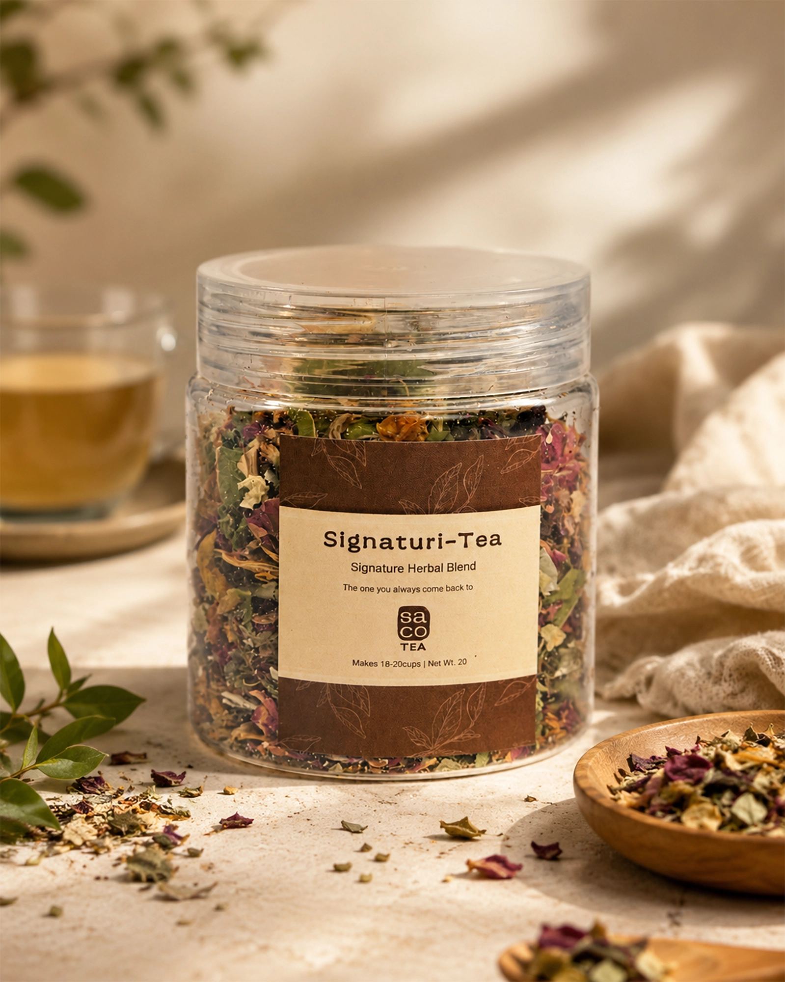 Jar of Signaturi-Tea with dried herbs on a table with a cup of tea and a wooden bowl.