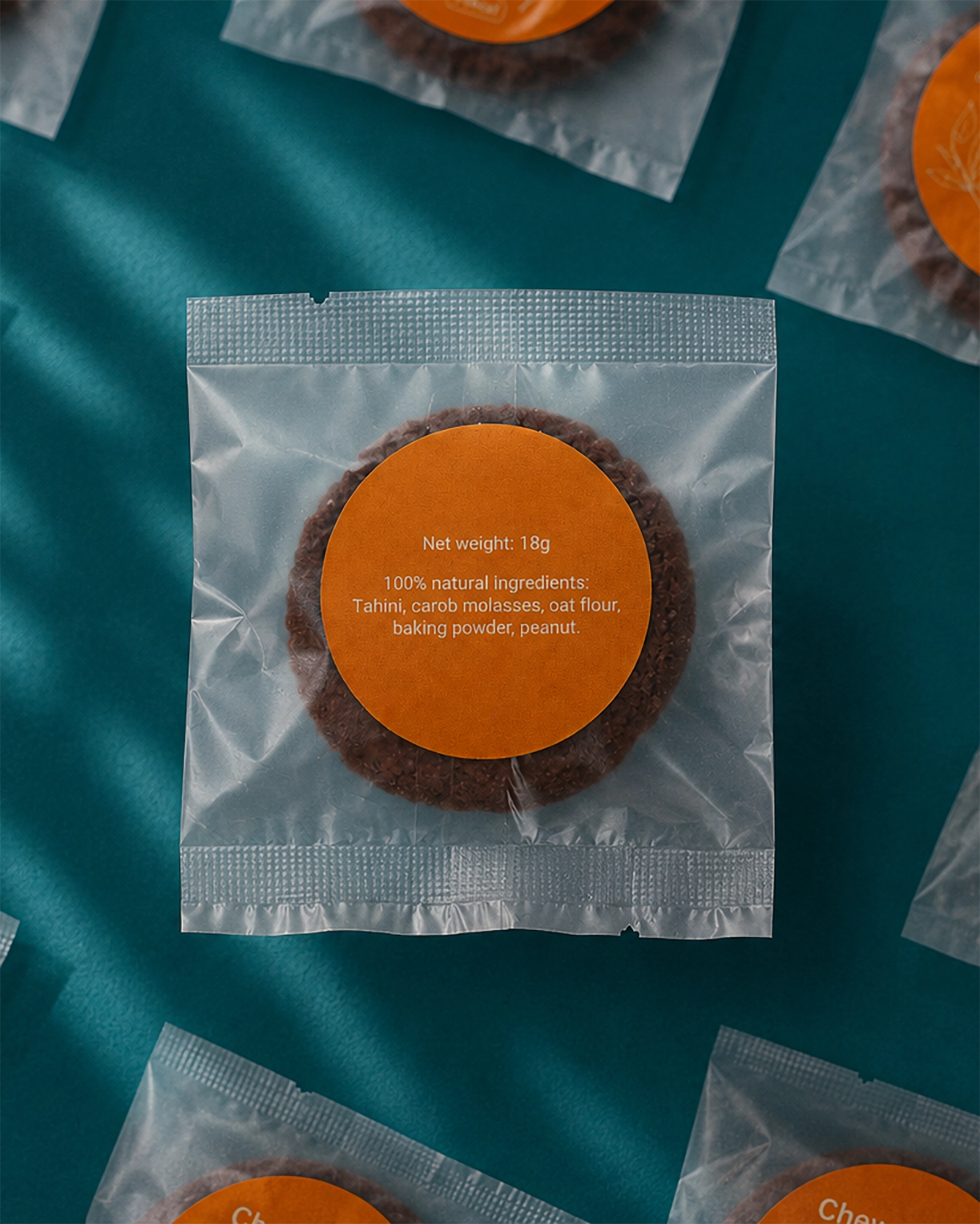Packaged cookie with an orange label on a teal background