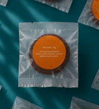 Packaged cookie with an orange label on a teal background