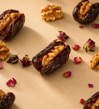 Blush Heart Dates stuffed with walnuts and scattered rose petals on a beige surface.