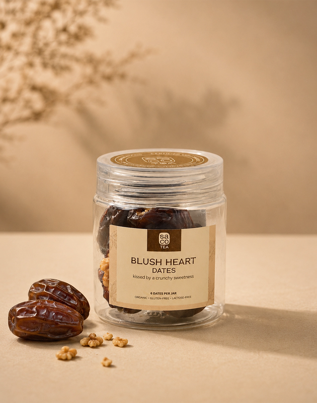 Saco Tea Blush Heart Dates jar with dates and crunchy toppings on a beige surface.