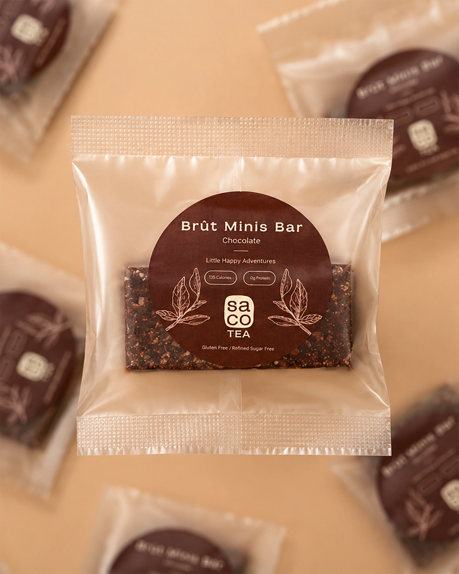 Packaged Brüt Minis Bar chocolate with brown label on a soft beige background.