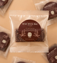 Packaged Brüt Minis Bar chocolate with brown label on a soft beige background.