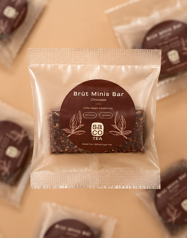 Packaged Brüt Minis Bar chocolate with brown label on a soft beige background.