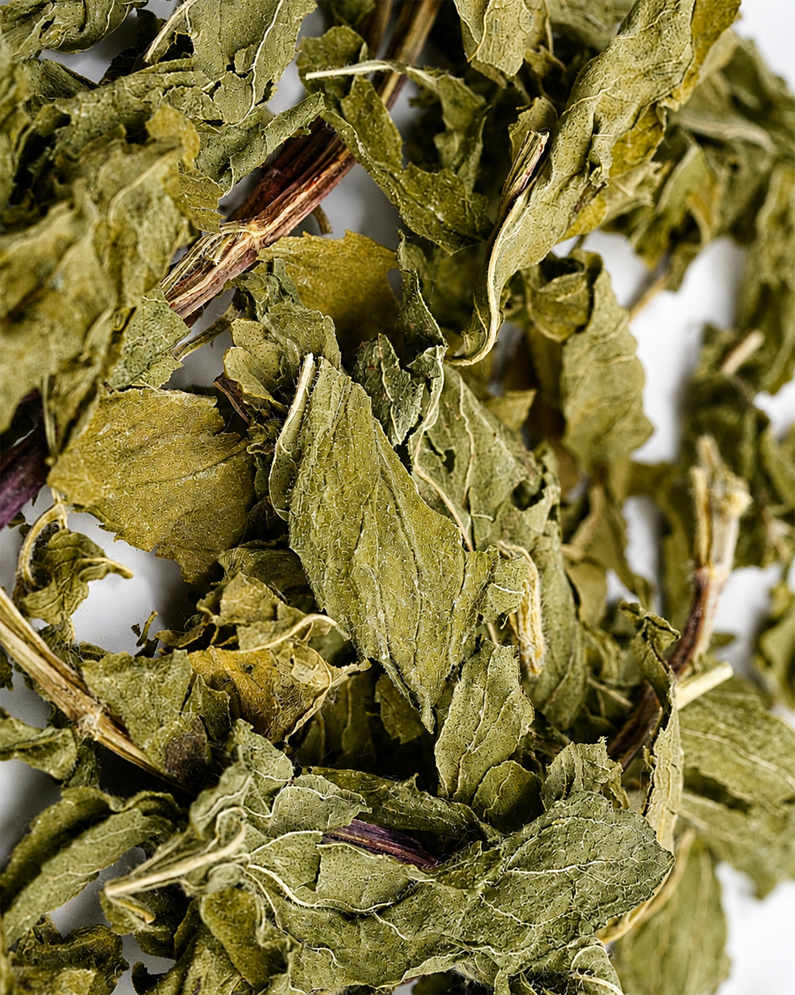 Close-up of dried Her Flow herbal tea leaves on a white background.