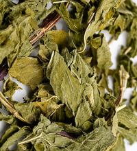 Close-up of dried Her Flow herbal tea leaves on a white background.