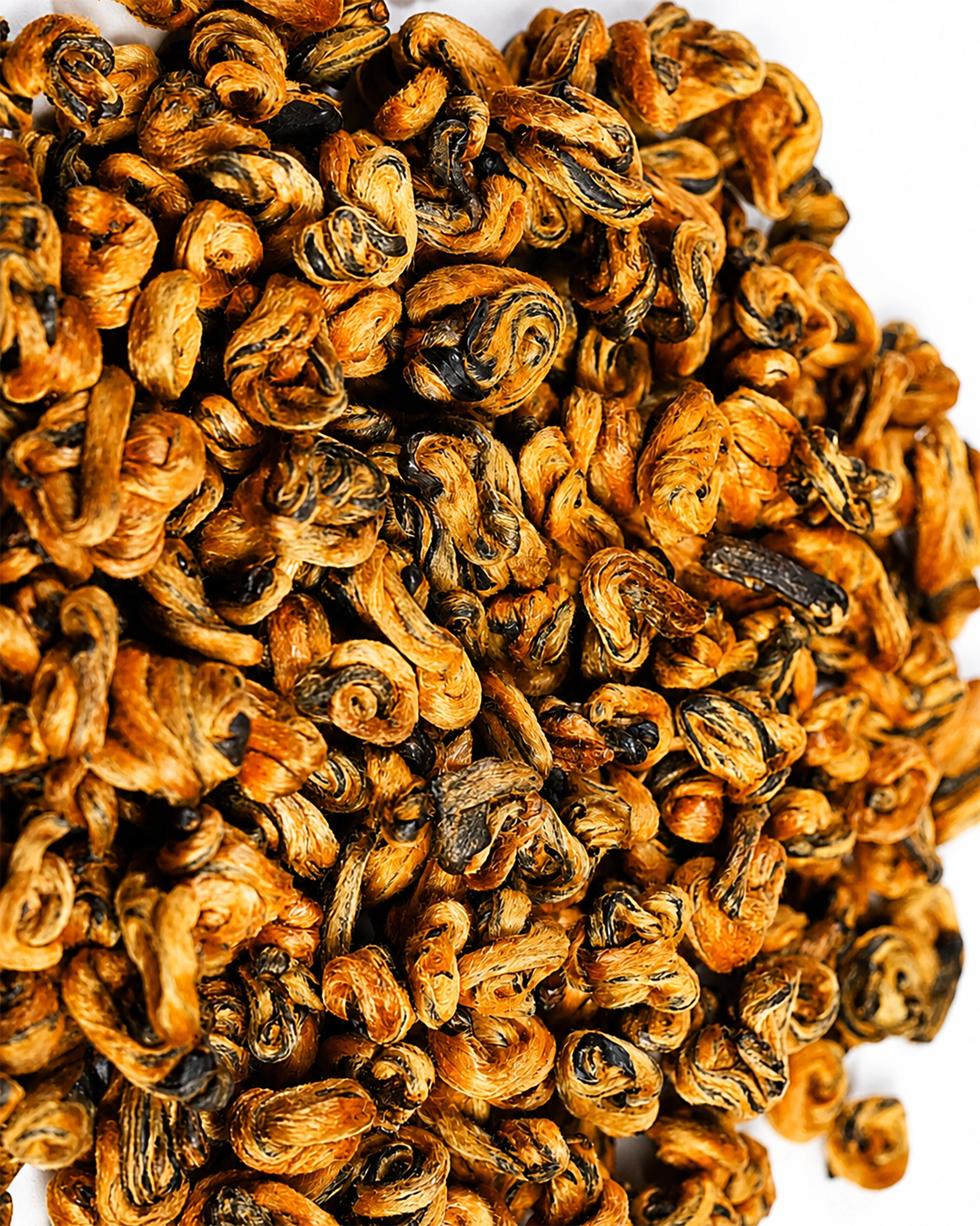 Close-up of Blacko Tea loose black tea leaves with golden curled tips on a white background