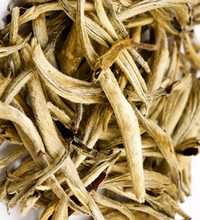 Close-up of loose white tea leaves on a white background.