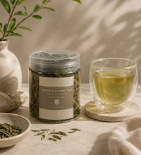 Sencha green tea jar, glass of tea, and tea leaves on a neutral background