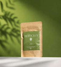 Saco Tea Japanese matcha powder pouch on a green background with soft leaf shadows.