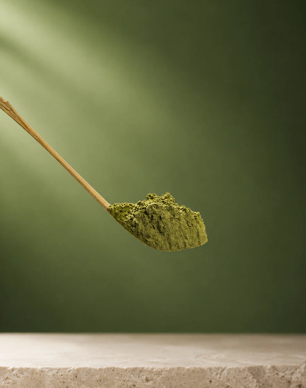 White package of matcha (500g) with a green label on a wooden tray with matcha powder and a whisk.