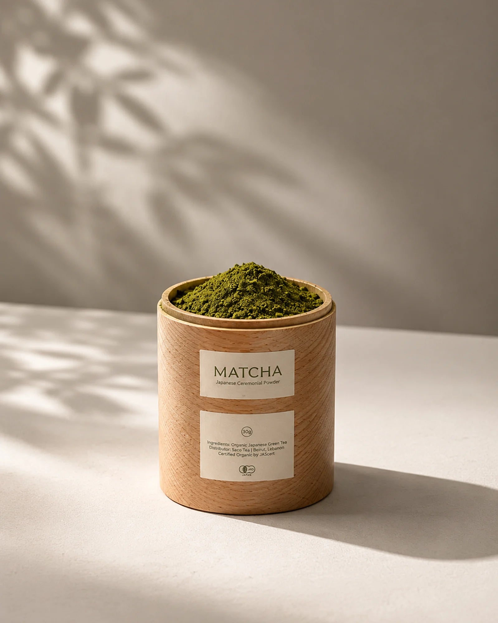 Container of matcha green powder with a label on a neutral background