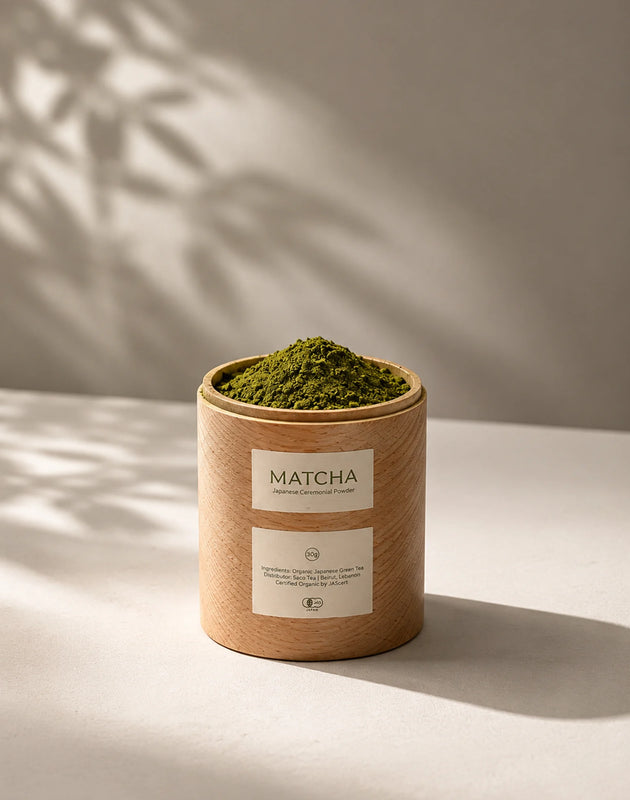 Wooden matcha container with a label on a wooden surface with a green leafy background