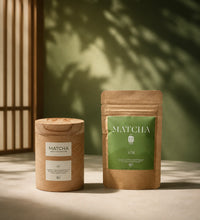 Saco Tea Japanese matcha powder pouch and wooden container on a light surface with soft greenery shadows.