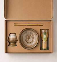 Open Saco Tea earthy matcha gift box with striped ceramic bowl, bamboo whisk, whisk holder, and bamboo scoop.