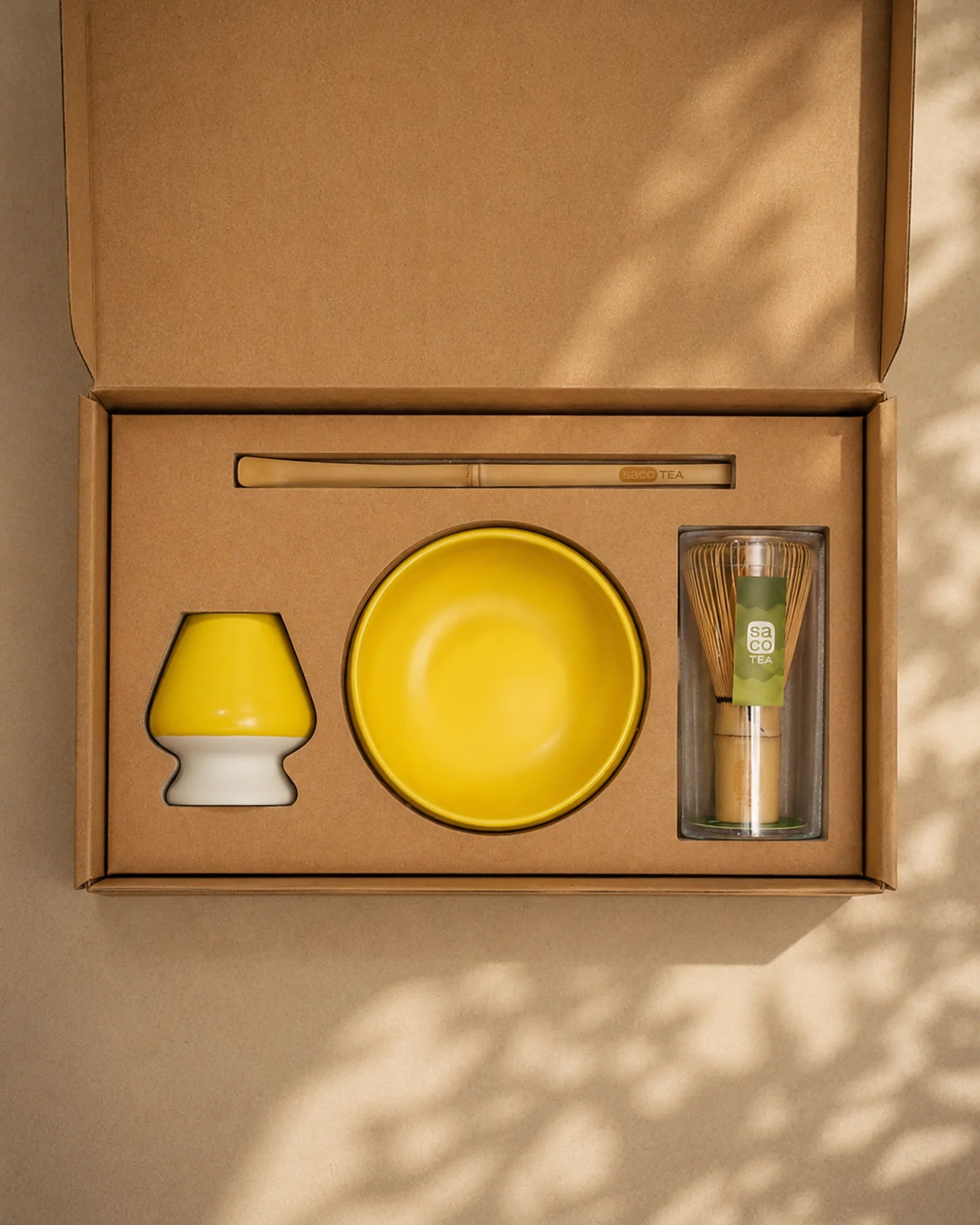 Open Saco Tea matcha gift box with yellow ceramic bowl, bamboo whisk, whisk holder, and bamboo scoop.