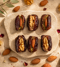 Date Duet stuffed dates with almonds and walnuts arranged on a textured stone plate.